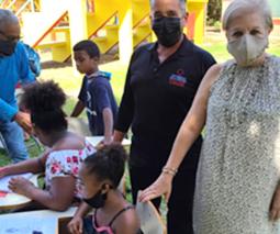 Imagen del Dr. Juan Ernesto Ayala, director de la oficina de Relaciones con la Comunidad junto a la alcaldesa de Loíza, Julia Nazario con varios niños haciendo actitvidades manuales. 