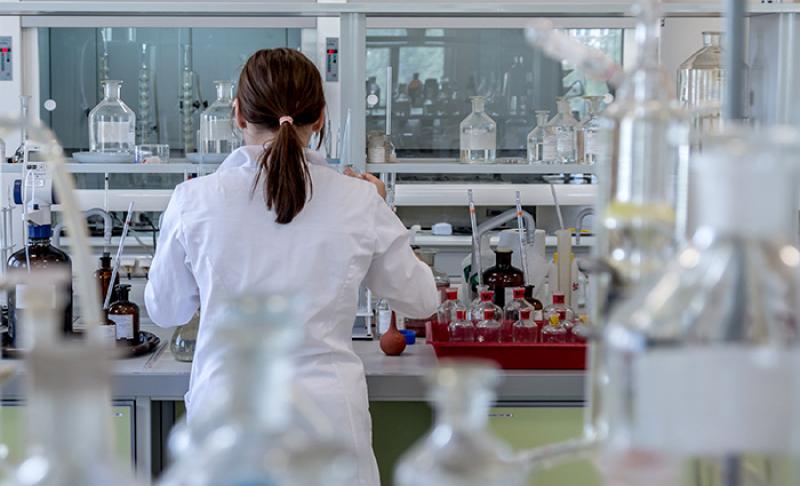 Imagen de una dama de espalda trabajando en un laboratorio químico