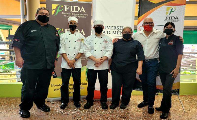 Varias personas vestidas de chef frente a un mostrador con comida