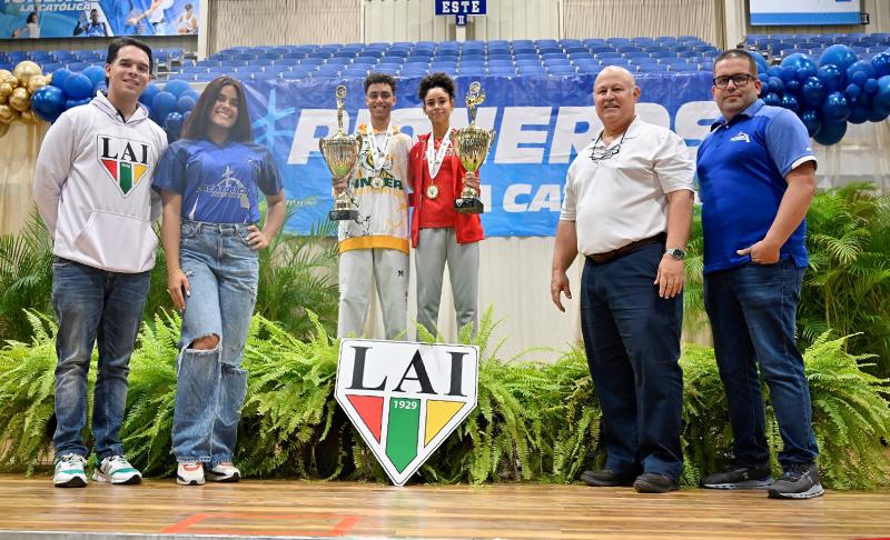 dos atletas de taekwondo mostrando los trofeos junto a cuatro entrenadores