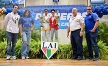 dos atletas de taekwondo mostrando los trofeos junto a cuatro entrenadores